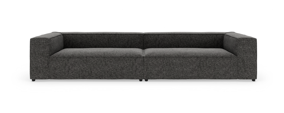 Mørkegrå, lav moderne modulsofa med brede armlæn set lige forfra, frilagt på hvid baggrund.