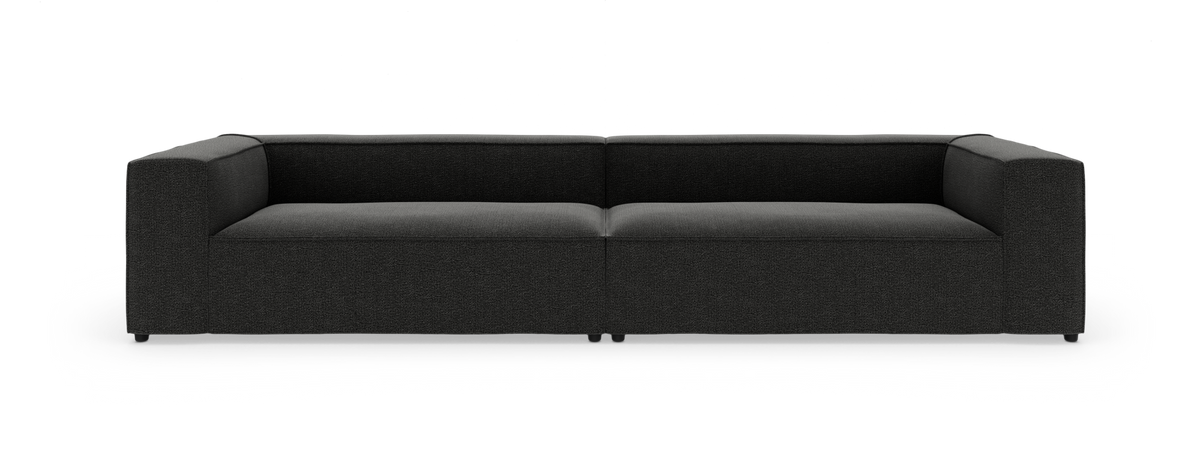 Mørkegrå modulsofa med brede armlæn, fotograferet lige forfra mod hvid studiebaggrund.