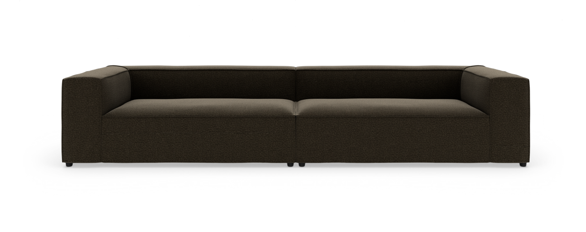 Mørkebrun, lav moderne modulsofa med brede armlæn, fotograferet lige forfra på hvid studiebaggrund.