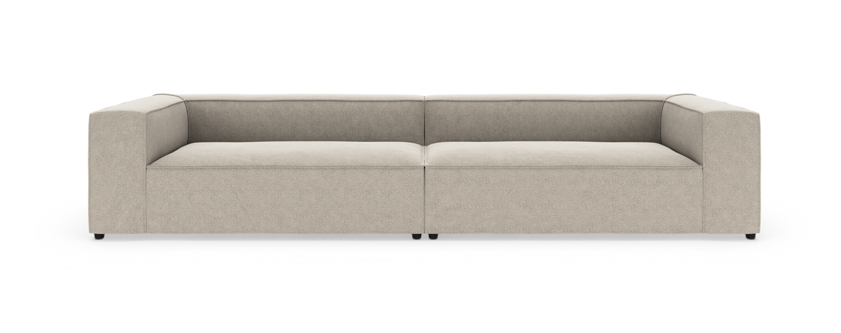Beige, lav modulsofa med brede armlæn, vist lige forfra på hvid baggrund.