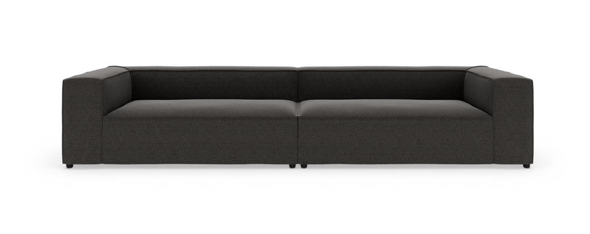 Mørkegrå, moderne modulsofa med brede armlæn, fotograferet forfra mod hvid studiobaggrund.