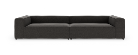 Mørkegrå, moderne modulsofa med brede armlæn, fotograferet forfra mod hvid studiobaggrund.