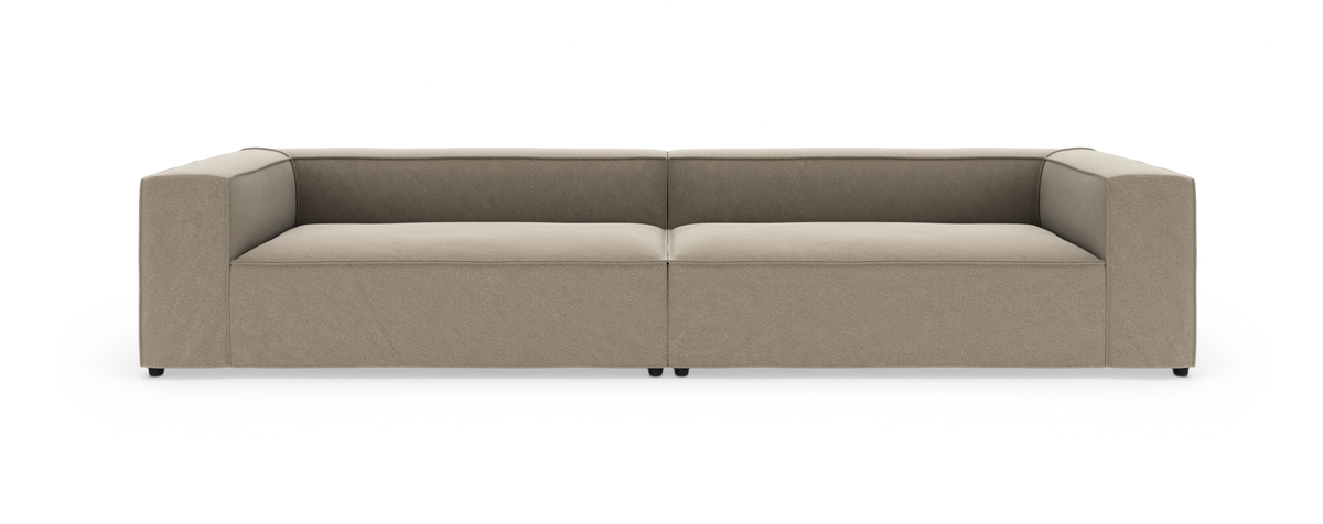 Beige modulsofa med lave ryglæn og brede armlæn, vist lige forfra på hvid baggrund.
