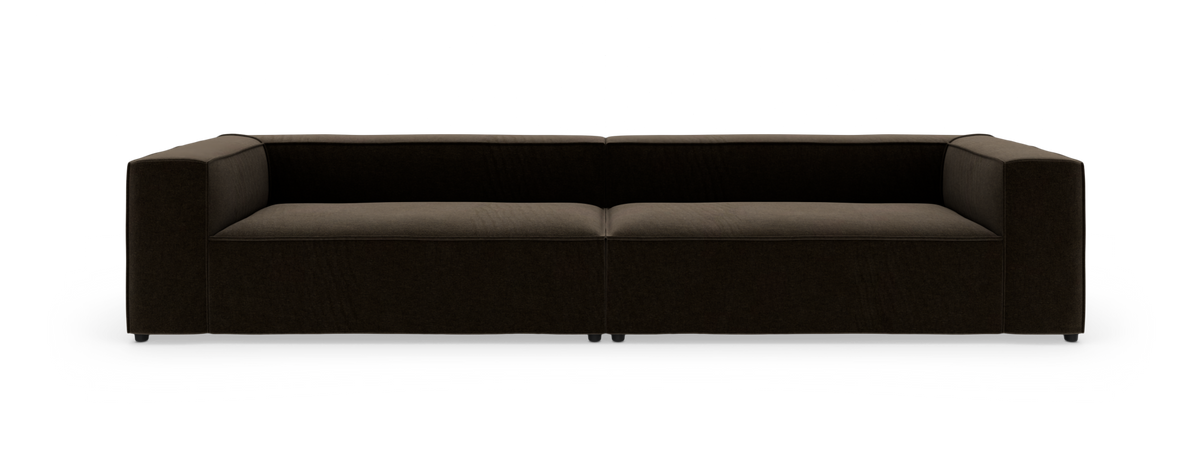 Mørkebrun, lav, moderne 3-personers sofa med brede armlæn, fotograferet lige forfra på hvid baggrund.