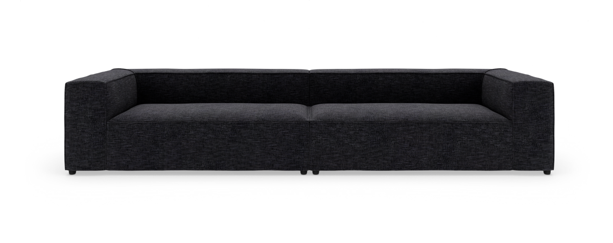 Lav, moderne sofa i mørkegråt stof på hvid studiobaggrund.