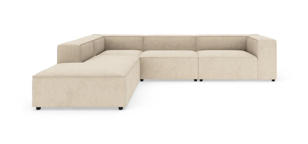 Beige modulsofa i L‑form med brede armlæn og lav siddehøjde på hvid baggrund.