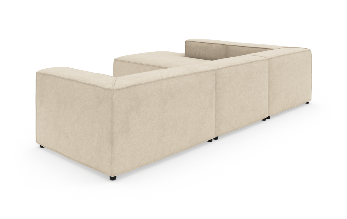 Beige modulsofa i U‑form set skråt bagfra på hvid studiobaggrund.