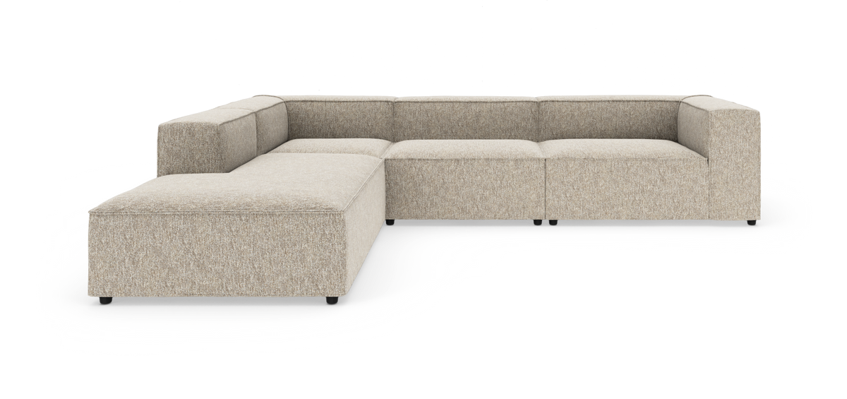 Beige modulsofa i L‑form med bred chaiselong til venstre, vist i studie mod hvid baggrund.