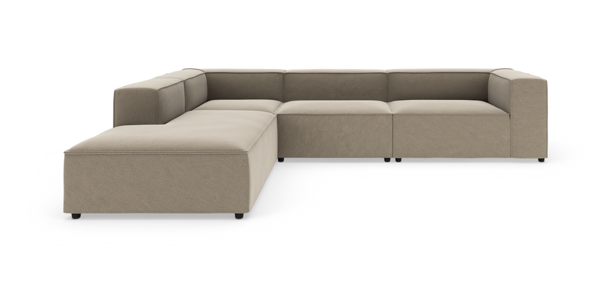 Stor L‑formet modulsofa i beige stof med brede armlæn, frilagt på hvid baggrund.