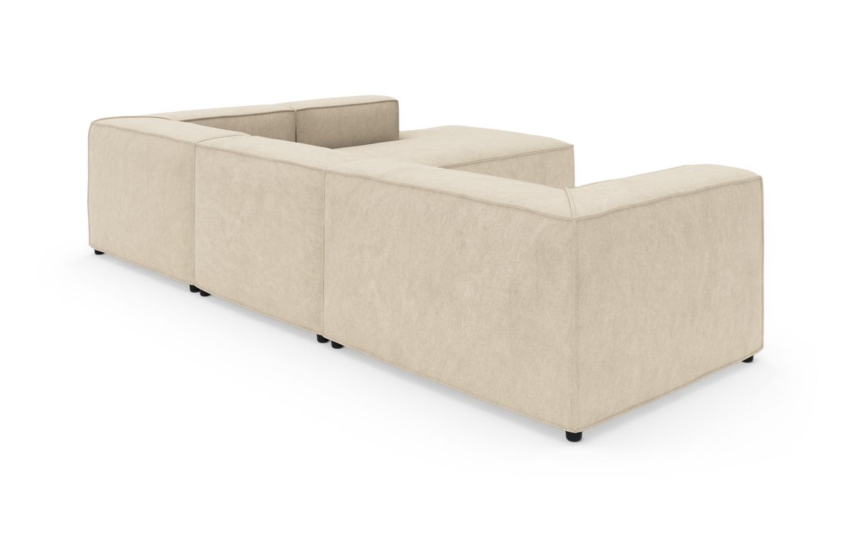 Beige modulsofa i U‑form set skråt bagfra på frilagt studio‑baggrund.