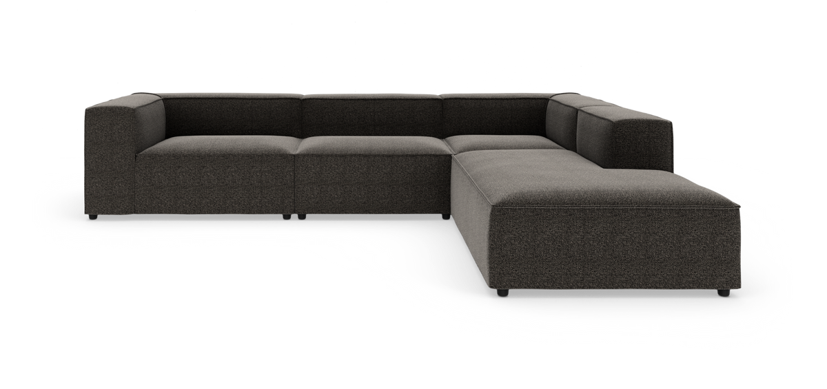 Modulsofa i mørkegrå L‑form, frilagt mod hvid baggrund i studie.