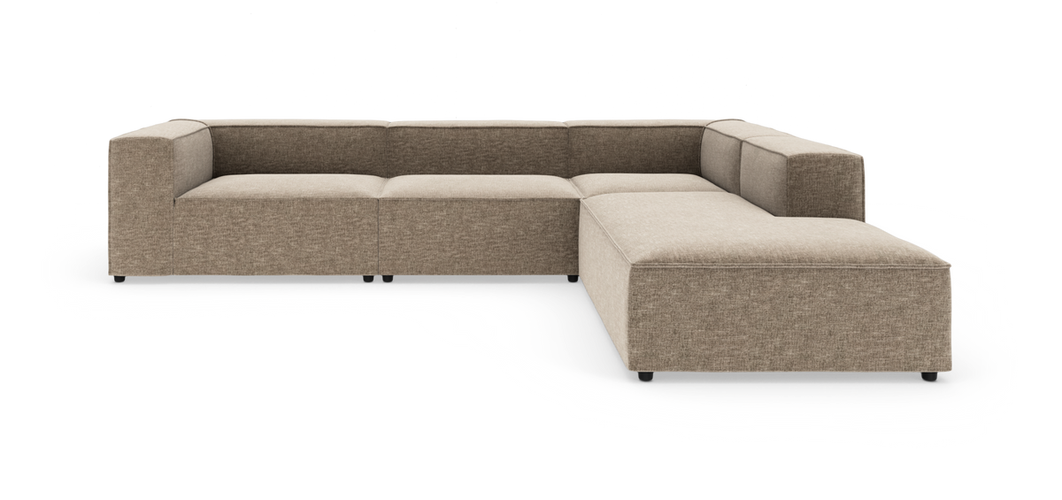 Modulær L-sofa i beige stof med brede armlæn og lav sædehøjde, vist i studiemiljø.