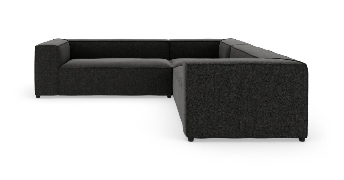 Modulær L‑sofa i mørkegråt stof på hvid studiebaggrund.
