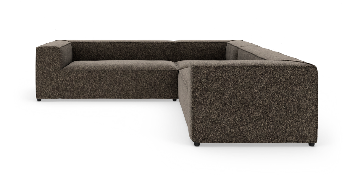 Modulær L‑formet sofa i mørkebrunt stof på studiebaggrund.