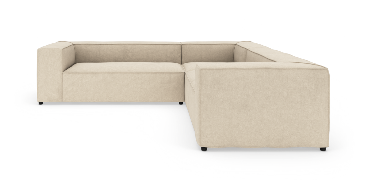 Beige U-formet modulsofa med brede armlæn og lav ryg, fritstående mod hvid studiobaggrund, set skråt forfra.
