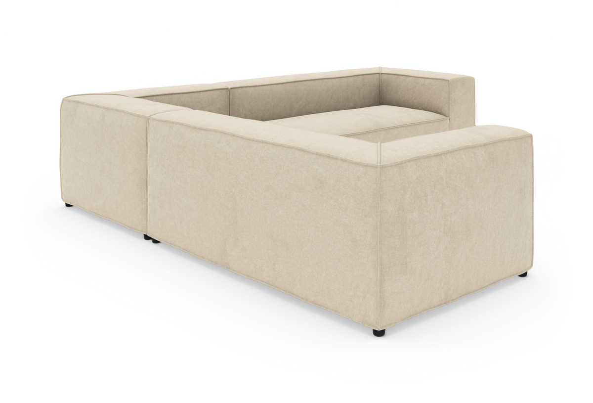Beige modulsofa i L‑form på hvid baggrund, fotograferet skråt bagfra.