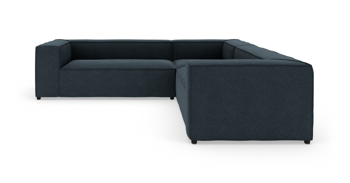 Mørk blå L‑formet modulsofa i studie på hvid baggrund.