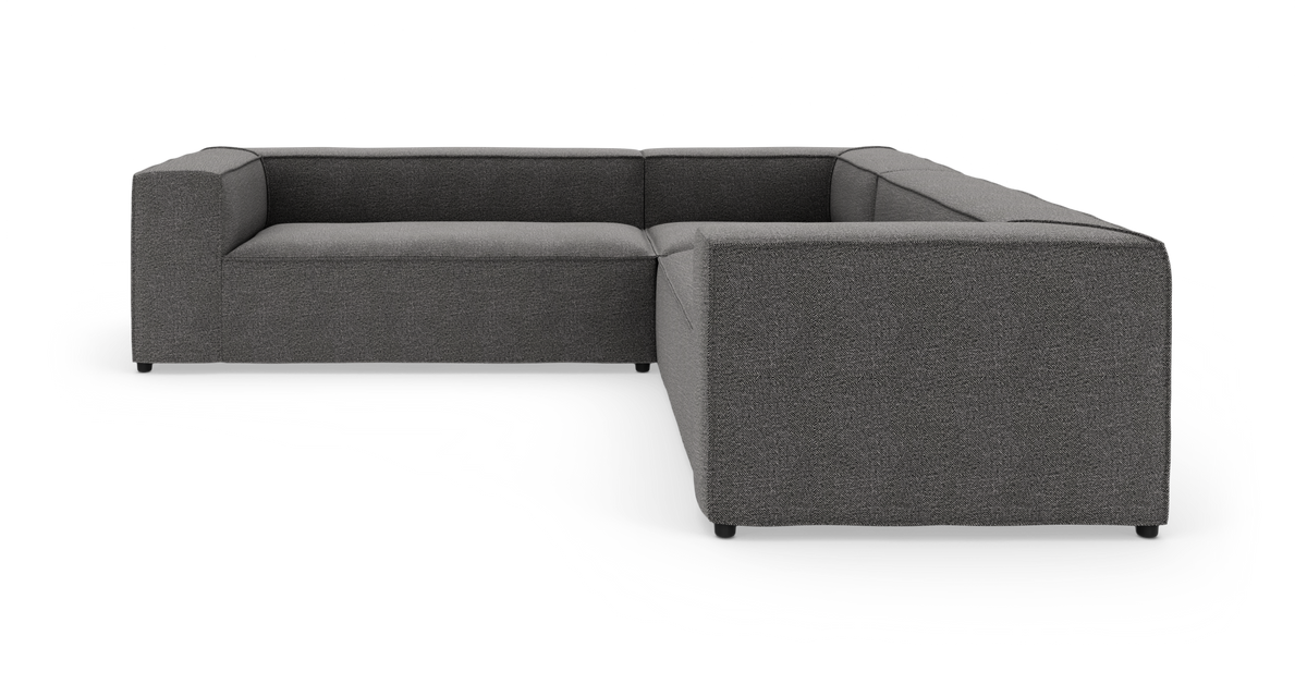 Mørkegrå L‑formet modulsofa i stof, moderne design på hvid studiobaggrund.