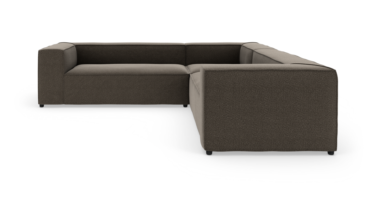 Modulær hjørnesofa i mørkegråt tekstil, L-form med lave armlæn og brede sæder, vist på hvid baggrund.