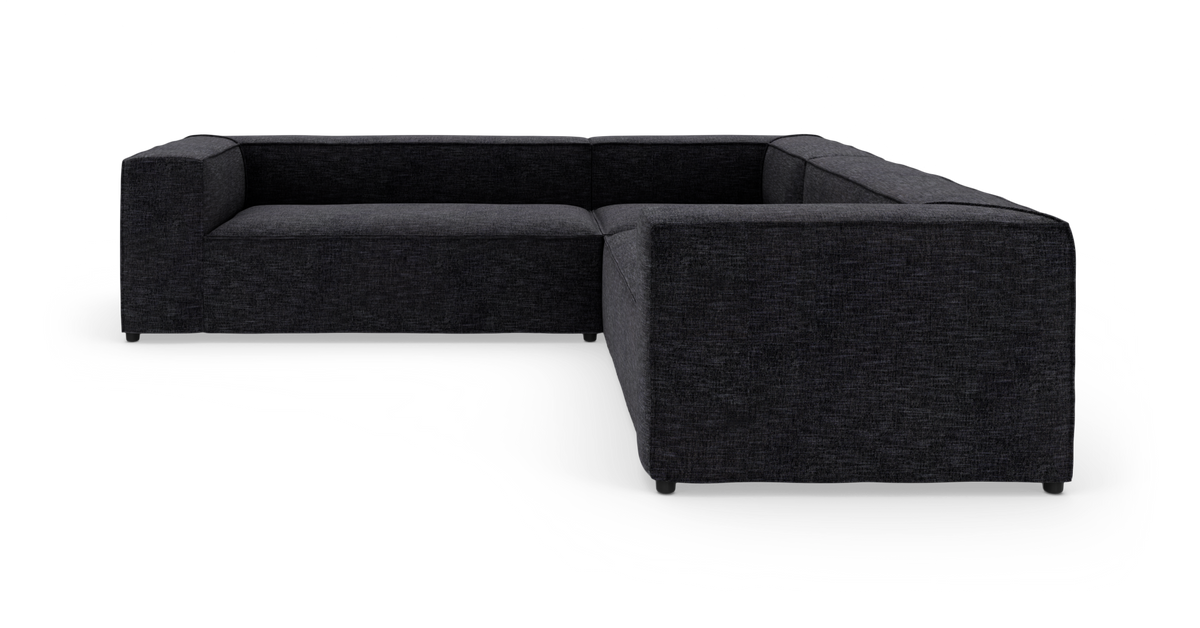 Mørkegrå L‑sofa i stof på hvid studiebaggrund.