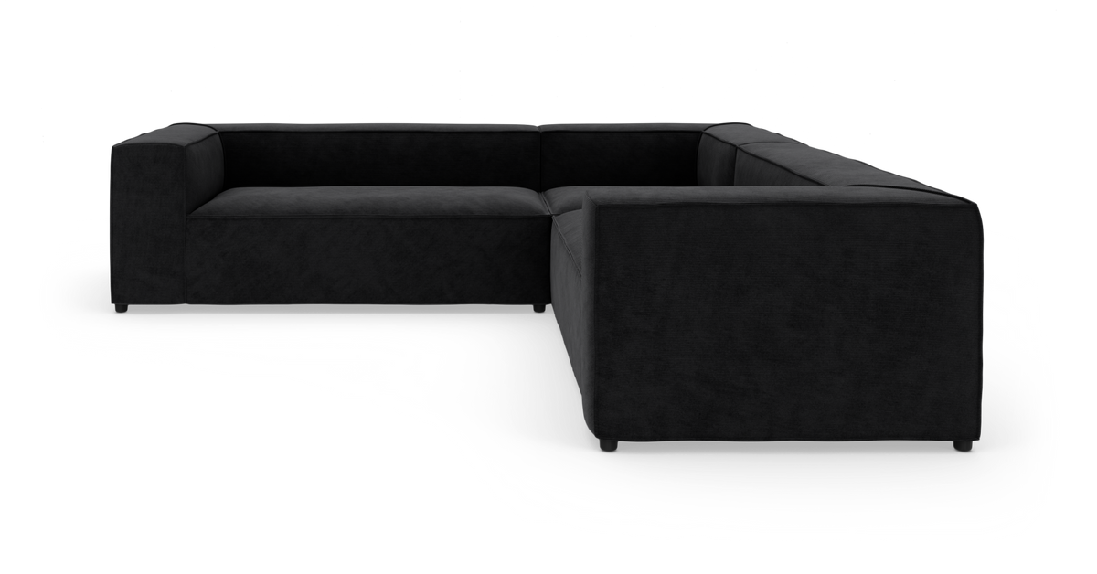 Sort modulsofa i L‑form på hvid baggrund, studiemiljø.