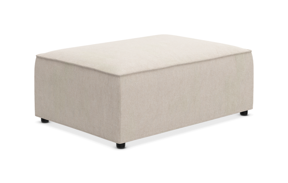 Beige rektangulær ottoman/fodskammel med blød polstring og små sorte fødder, frilagt på hvid baggrund.