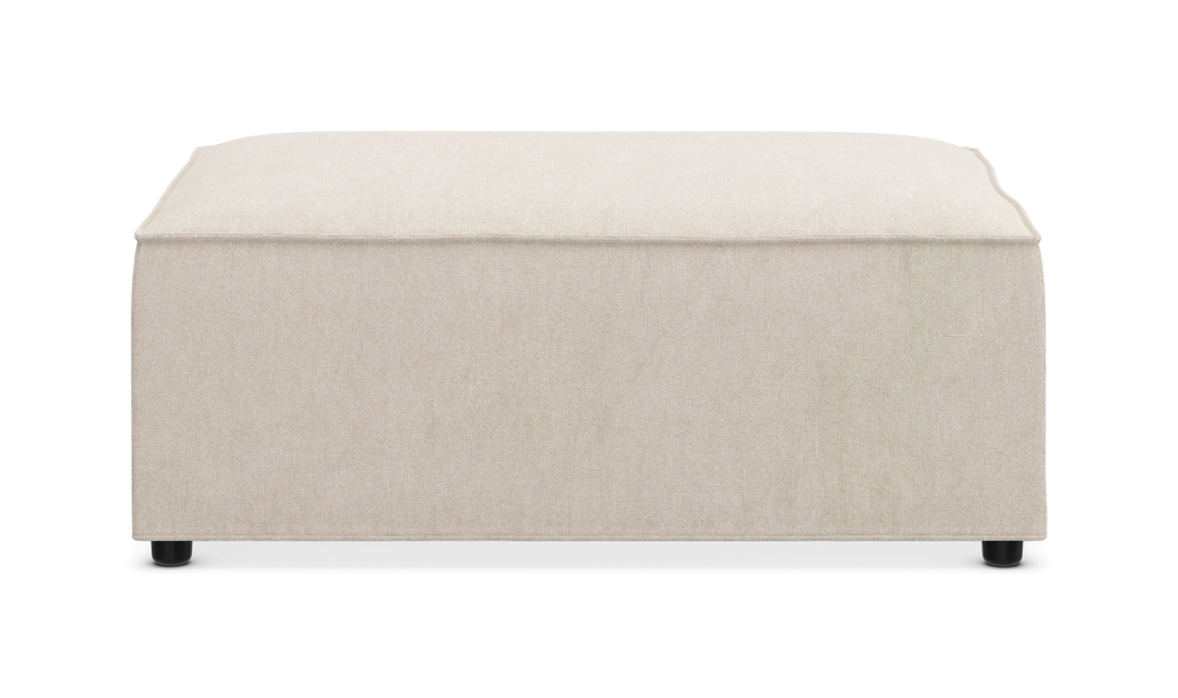 Beige kvadratisk puf/ottoman i stof med små sorte fødder, frontvisning.