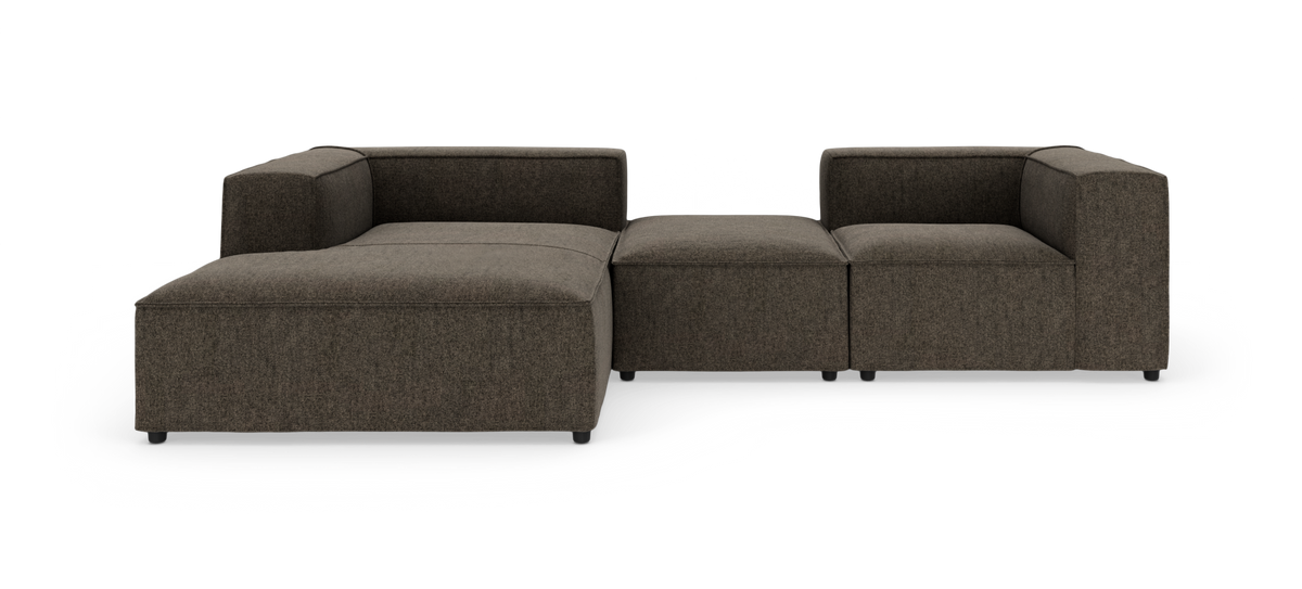 Modulsofa i mørkebrunt stof med chaiselong til venstre og midterpuf, frilagt mod hvid baggrund, set forfra.