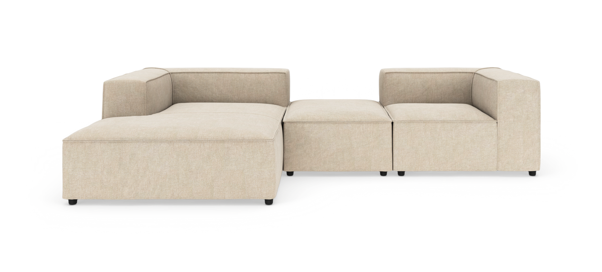 Beige modulsofa i stof med venstrevendt chaiselong og højre hjørnemodul, fotograferet mod hvid baggrund.