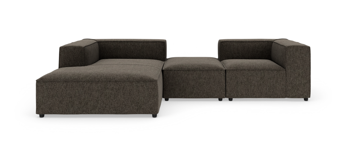 Modulsofa i mørk grå/brun tekstil med lave ben, tre sektioner og åben chaiselong til venstre, frilagt på hvid baggrund.