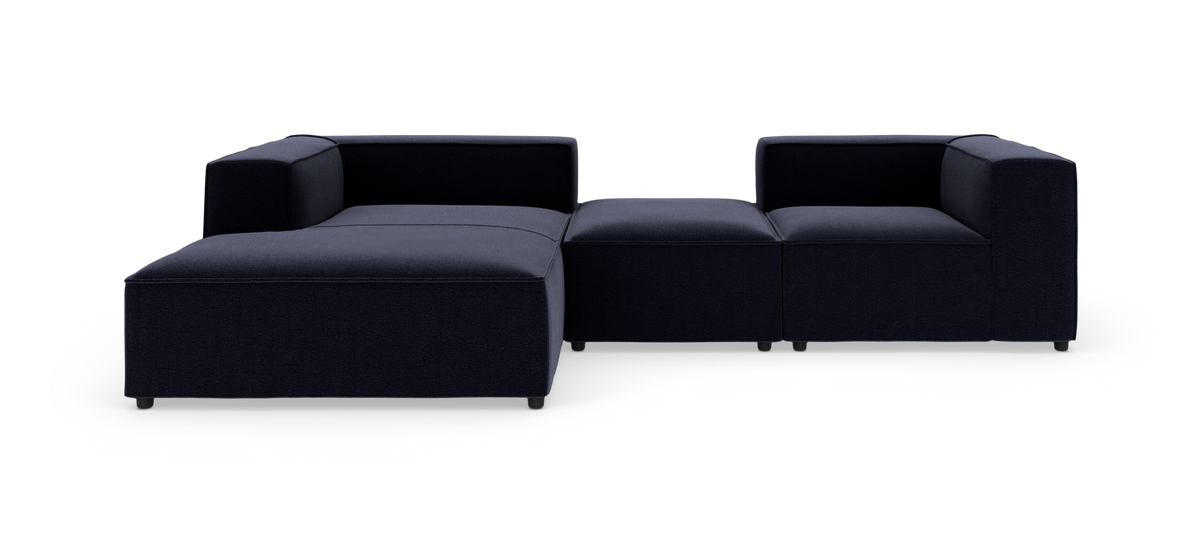 Modulær mørkeblå sektionsofa i tekstil med chaiselong til venstre, fritlagt på hvid baggrund.
