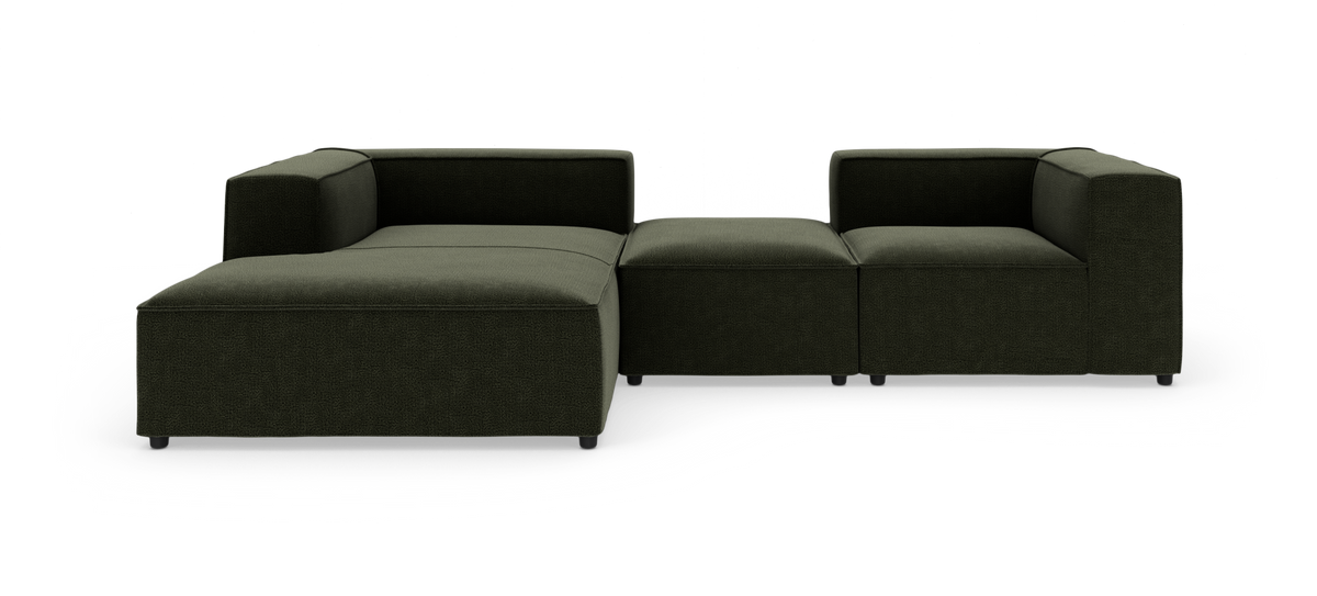 Modulsofa i mørkegrønt stof med venstre chaiselong og højre hjørnemodul, fritlagt i studie.