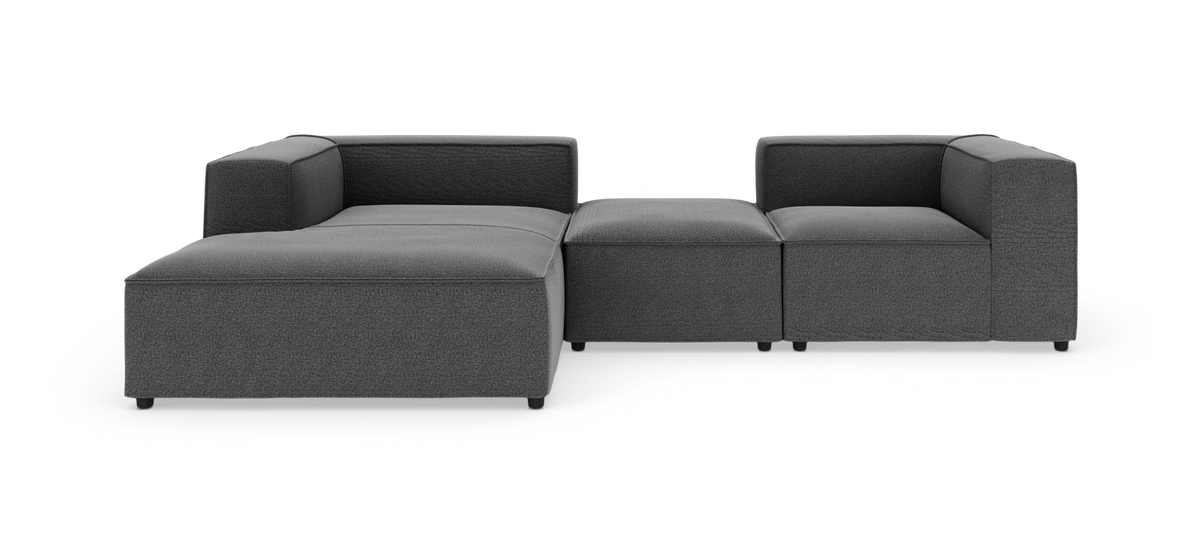 Modulsofa i mørkegråt stof, L‑form med chaiselong til venstre, fritstående på hvid baggrund.