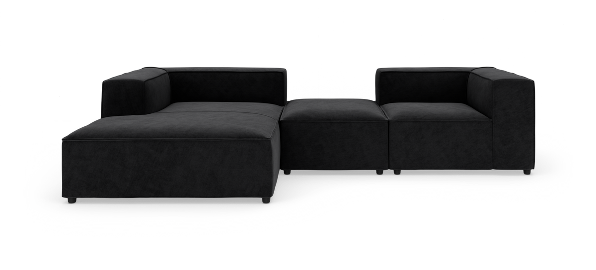 Sort modulsofa i stof med venstre chaiselong, midterpuf og højre hjørnemodul, frilagt på hvid baggrund, frontvisning.