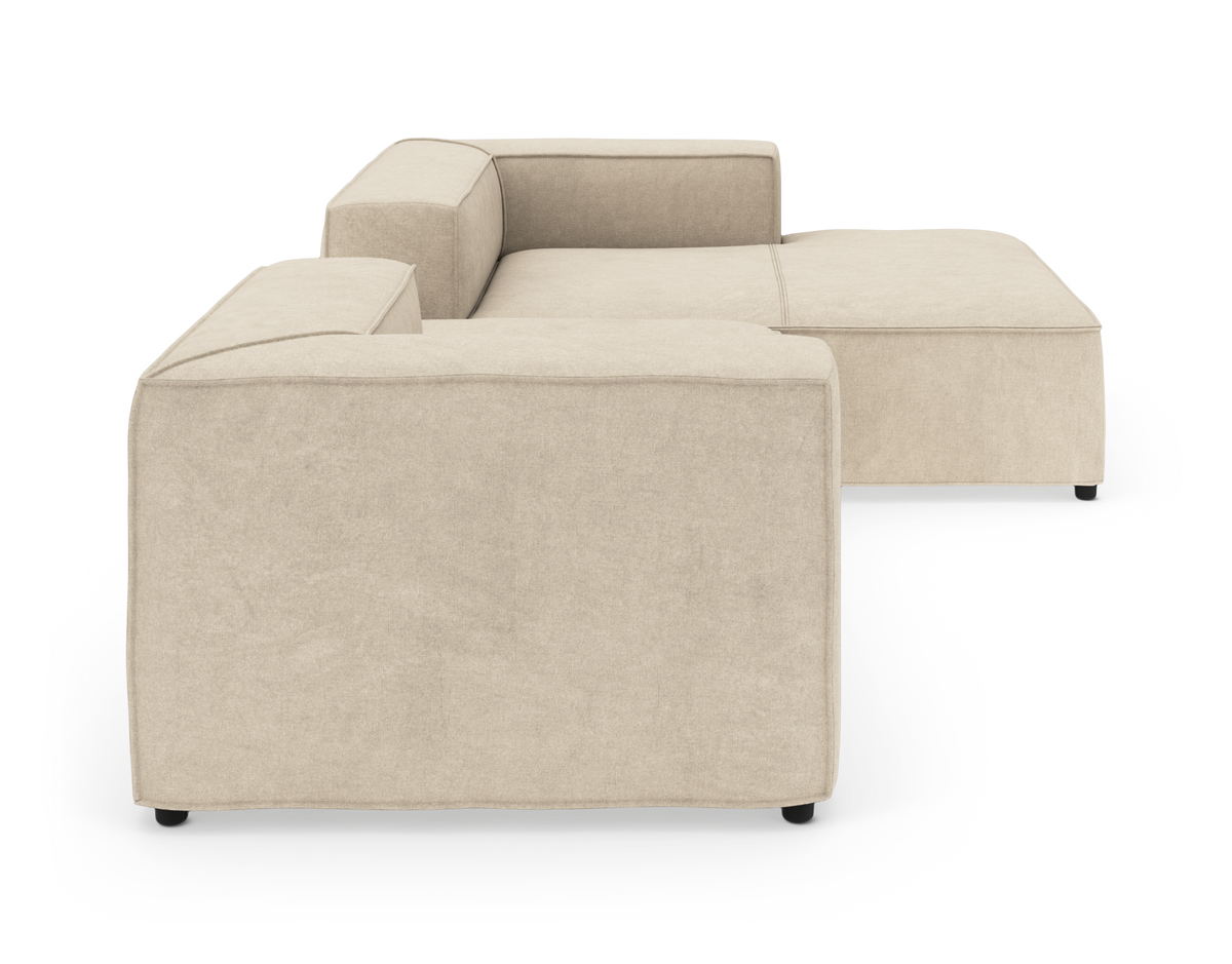 Beige modulsofa med chaiselong set bagfra i studieisolering.