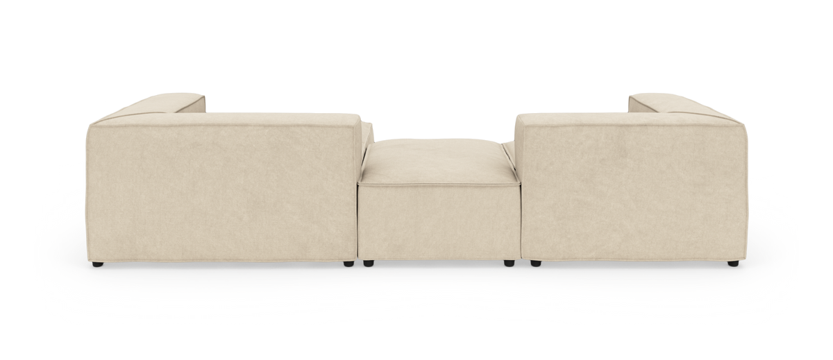 Beige modulsofa set bagfra med lav midterpuf på hvid studiebaggrund.