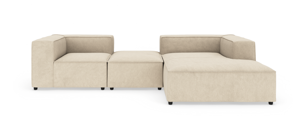 Beige modulsofa i L‑form med chaiselong, frilagt mod hvid baggrund i frontvisning.