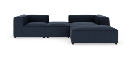 Modulsofa i mørkeblåt stof, L‑form med bred chaiselong og lave armlæn, produktfoto på hvid baggrund.