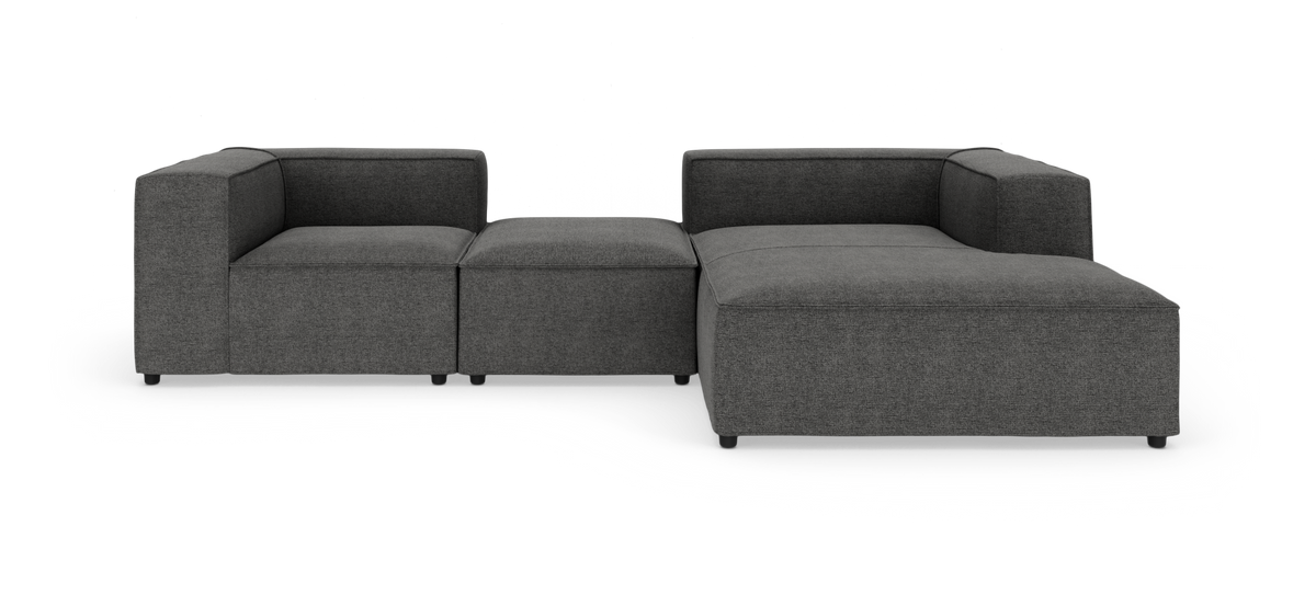 Modulsofa i mørkegråt stof med venstrehjørne, midterpuf og højre chaiselong, frilagt på hvid baggrund.