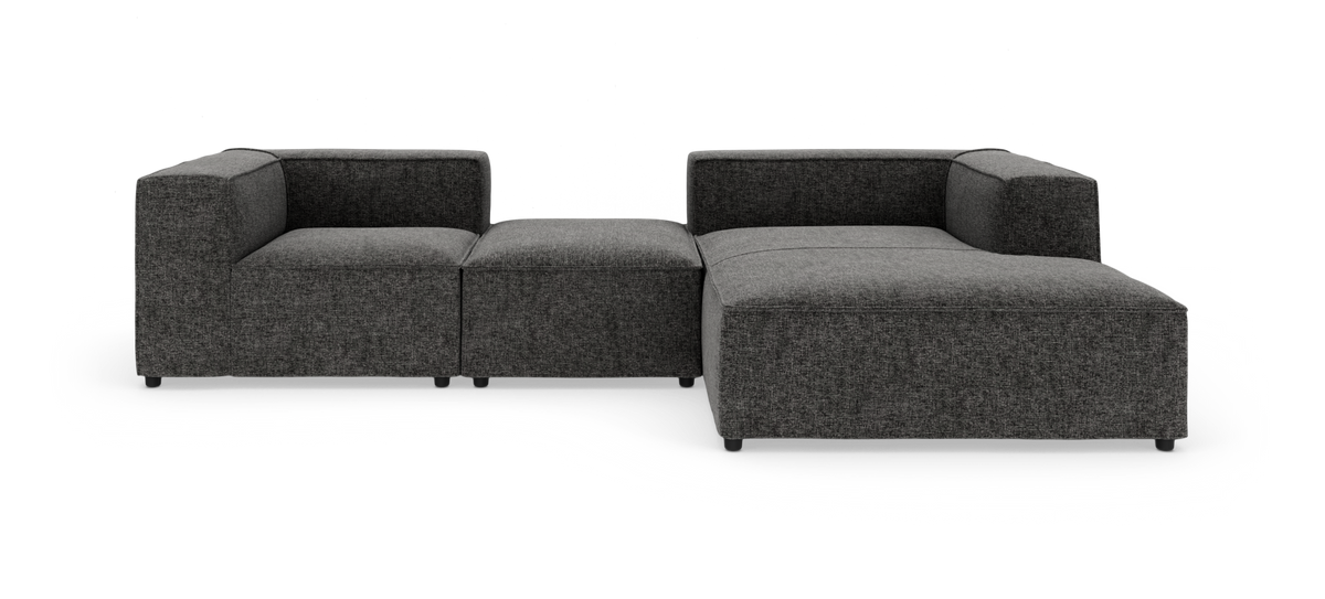 Modulsofa i mørkegråt stof i L‑form, frilagt på hvid baggrund.