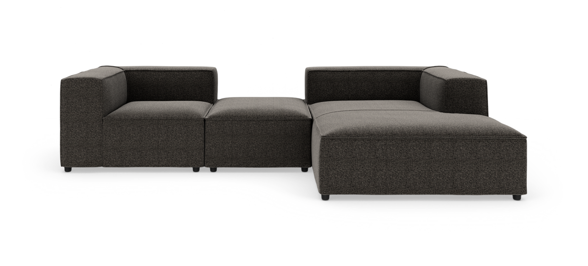 Modulær mørkegrå hjørnesofa med chaiselong og midterpuf, frilagt på hvid baggrund.