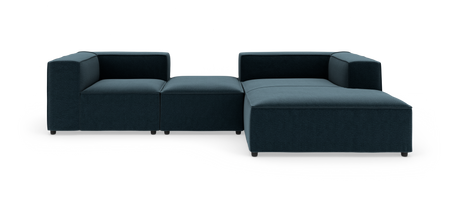 Mørkeblå modulsofa i stof med lav profil og chaiselong, frilagt på hvid baggrund.