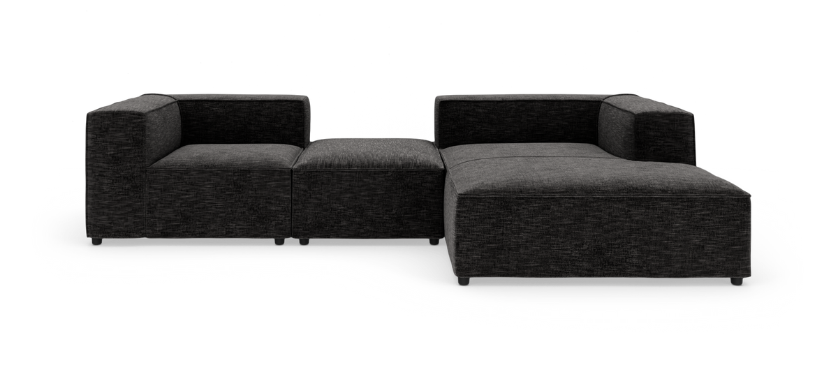 Modulær mørkegrå hjørnesofa i stof med bred chaiselong på højre side.