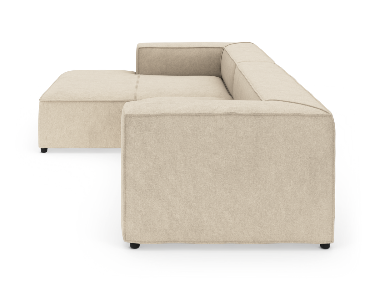 Beige L‑formet modulsofa i stof, fritlagt på hvid baggrund, set skråt fra siden.