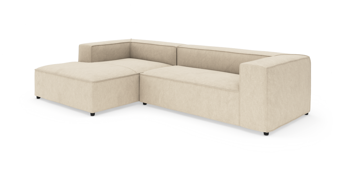 Beige modulsofa i L-form med chaiselong, moderne og lav, isoleret på hvid baggrund.