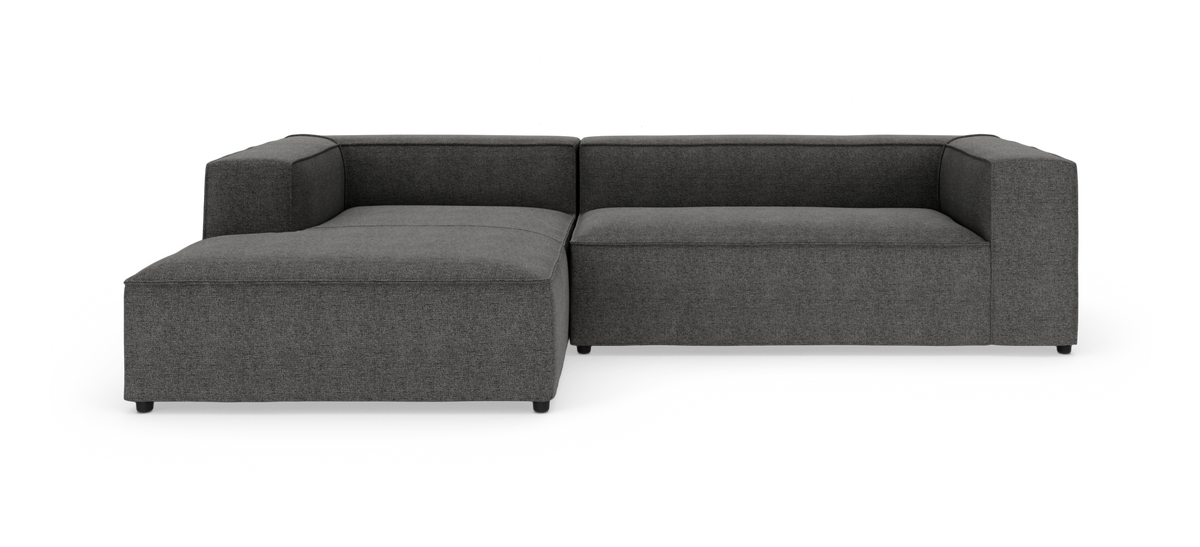 Mørkegrå L‑sofa med venstre chaiselong og kantede armlæn, isoleret mod hvid studiobaggrund.
