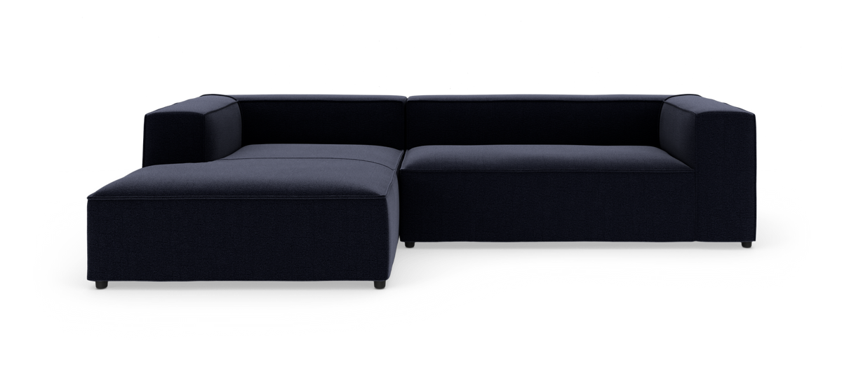 Mørkeblå L-formet modulsofa i studio på hvid baggrund.