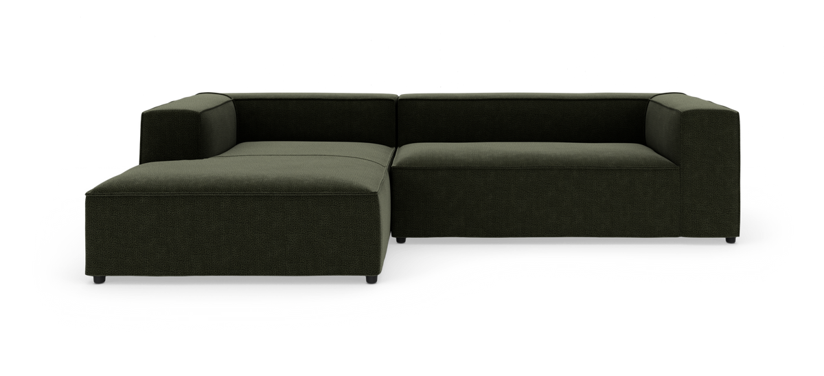 Mørkegrøn modulsofa i L-form på hvid studiobaggrund.