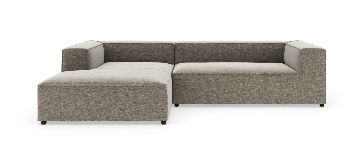 Modulær hjørnesofa i L-form i grå-beige stof, fotograferet mod hvid studiobaggrund.