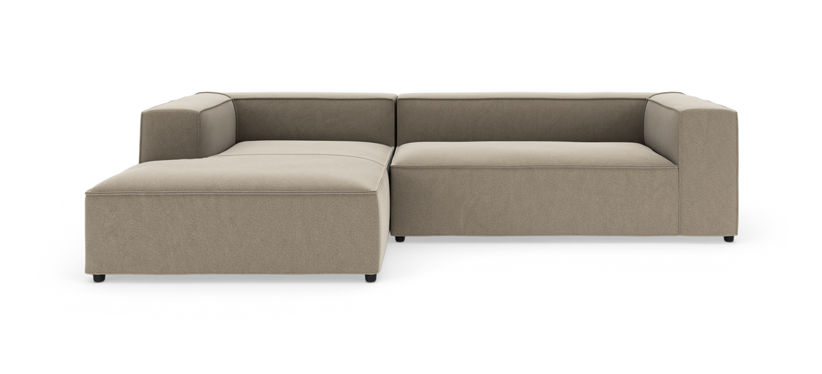 Beige modulsofa i L‑form med venstrevendt chaiselong, frilagt på hvid baggrund.